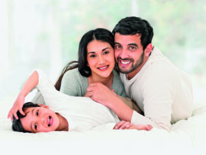 little indian boy lying on bed with his parents