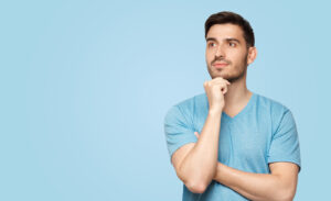 Banner of young man in blue t-shirt with dreamy cheerful expression, thinking