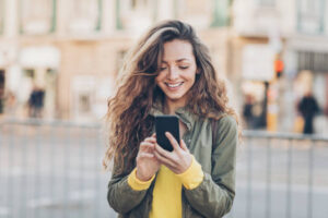 Young woman with smart phone texting outdoors in the city