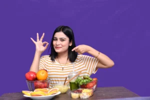 foodie-girl-sitting-fruit-table-smiling-ok-hand-sign-indian-pakistani-model-scaled